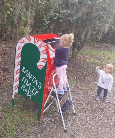 Little girl puts letter in Santa's mailbox.